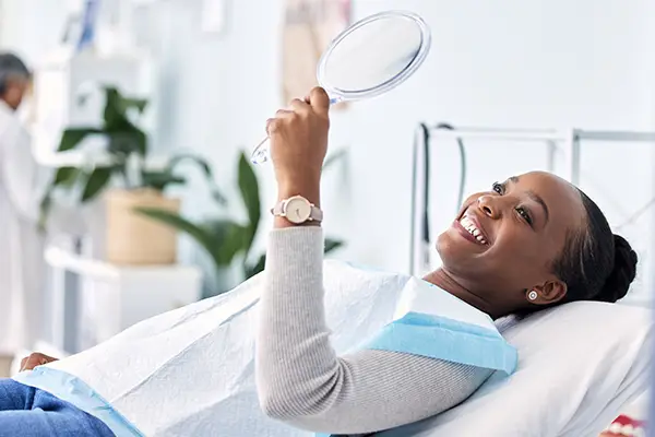 Black woman holding hand held mirror atBrian K. Rounds, DDS in Lacey, WA